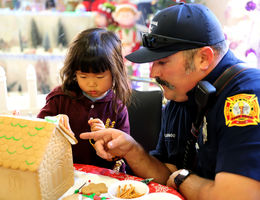 Firefighter helps young girl decorate gingerbread house