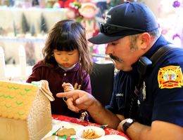 Gingerbread Village 2018 Firefighter helps young girl decorate gingerbread house