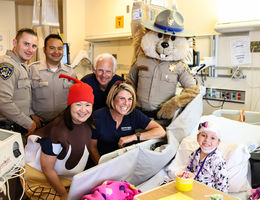 visitors pose by bedside of young female patient for photo