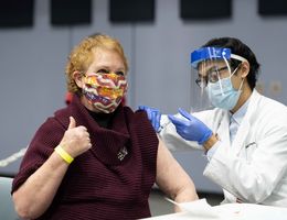 Patient receives COVID booster shot while giving a thumbs up