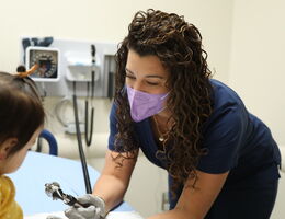 Female doctor wearing a mask examining a toddler in a hospital room