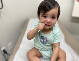 female toddler sitting on doctor's exam table clearly upset