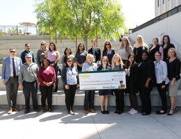 smiling group of male and female hospital staff, administrators, and Farmer Boys representatives pose for photo with presentation check