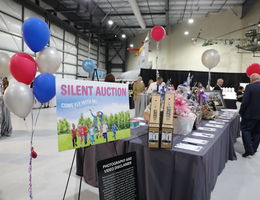 Silent auction sign next to table with a black tablecloth, donned with items displayed at an event