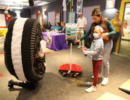 Young patient stands next to her mom and interacts with Oreo charactter at Community Day