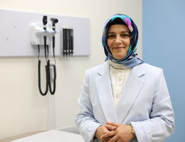 Dr. Orsdemir standing in clinic room looking and smiling at camera