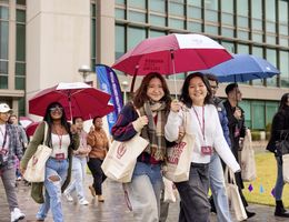 a group pf young adults holding umbrellas walking in the rain