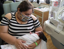 masked mother holds tiny baby