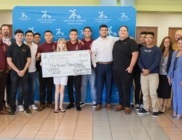 fraternity members stand with patient holding check