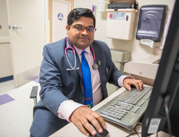 young indian doctor sits in front of computer 