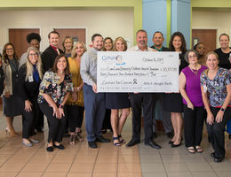 male and female staff and admin from both organizations pose with giant check