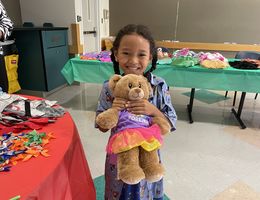 Girl patient hold brown teddy bear and smiles at camera