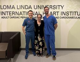 a woman poses with two men beside her all smiling 
