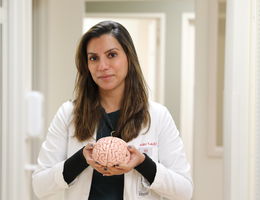 Dr. Maninder Kaur holds a three-dimensional model of the human brain
