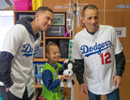 two baseball players pose for picture with young male patient