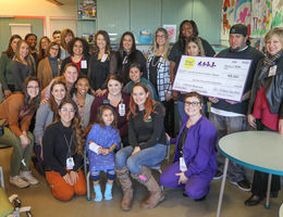 hospital staff, store staff and patient pose with check