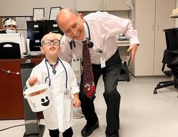 Dr. Khearapour bent down next to his pediatric cancer patient who is dressed up as a doctor