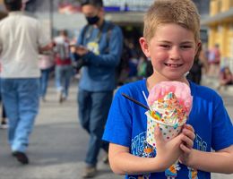 young Caucasian boy in blue t-shirt holding a candy ice cream sundae