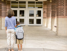 Nervous boy. First day of school. Holds on to mom. stock photo