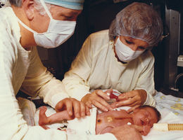 Surgeon Leonard Bailey and immunologist Sandra Nehlsen-Canarrella spend time with Baby Fae following her historic surgery.
