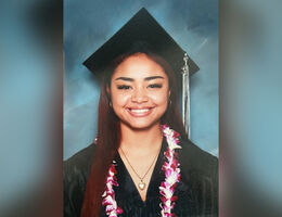 Abigail Aguilar smiling in a cap and gown in a formal graduation photo. 