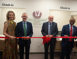 Group of two women and three men in business attire for a ribbon cutting ceremony