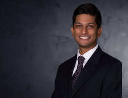dark-skinned man in black suit and tie portrait style