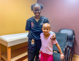 female doctor stands with female patient next to wheelchair, both smiling