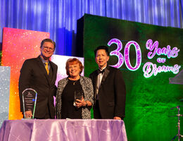 Caucasian man, Caucasian woman and Asian man in formal wear, presenting an award.  man, 