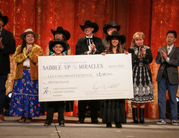 group wearing country-themed attire, including two young children, present a large check