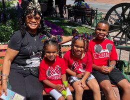 Gaylyn sitting on bench at Disneyland with her three grandchildren. Two girls, one boy