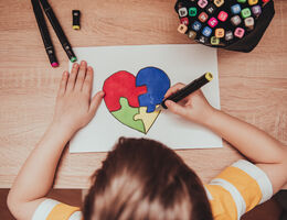World Autism Awareness day. Children's hand draws heart from multi-colored puzzles. Mental health care concept