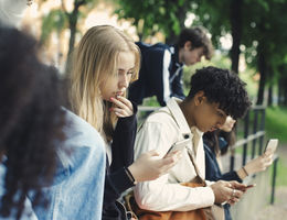 Male and female friends using smart phones in park - stock photo