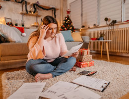 Woman sitting in holiday-decorated living room, looking stressed out.