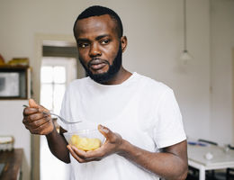 man standing holding bowl of food looking stressed
