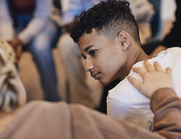 Teenage boy looking at female friend consoling in group therapy