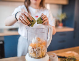 Woman puts kiwi in a blender - stock photo