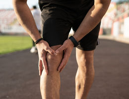 Unrecognizable sports man injures his knee while jogging 