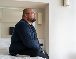 Middle aged white man sitting on bed stressed out