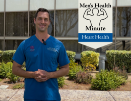 A white doctor in blue scrubs stands in front of a medical building outside and talked to the camera.