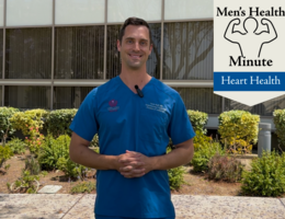 A white doctor in blue scrubs stands in front of a medical building outside and talked to the camera.