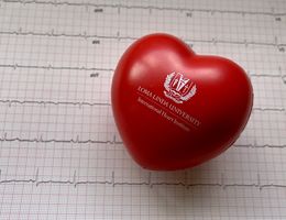 Red heart-shaped stressball against backdrop of ECG printout