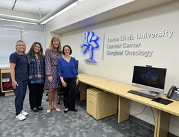 Left to right: Megan Getman, LVN supervisor at Cancer Center, Yolanda Hernandez, RN manager at Cancer Center, Judy Chatigny Cancer Center executive director, Kristina Chase director of oncology services at Cancer Center. Four women stand to the left and pose next to a wall sign reading "Loma Linda University Cancer Center Surgical Oncology"