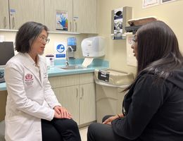 Sharon Lum, MD, MBA, chair of the LLUH Department of Surgery speaks with a breast cancer patient in a clinic room.