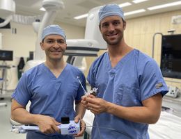Structural interventional cardiologists Drs. Amr Mohsen (left) and Jason Hoff (right) hold the device they used to perform Gail Perszyk's mitral transcatheter edge-to-edge valve repair.