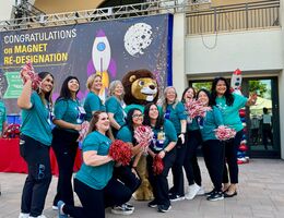 Group of people outside in matching teal t-shirts smiling at the camera