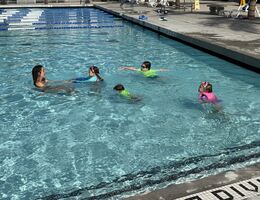Four kids swimming towards swim instructor at the Drayson Center pool