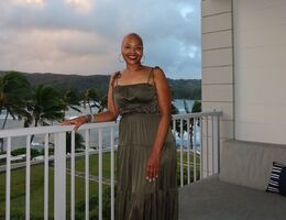 Sonja Loadholt stands on balcony overlooking beach and palm trees