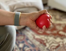 Person squeezing a heart-shaped stress ball