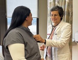 A doctor examines a patient's heart using a stethoscope. 